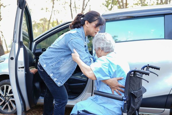 Help and support asian senior or elderly old lady woman patient sitting on wheelchair prepare get to her car : healthy strong medical concept.